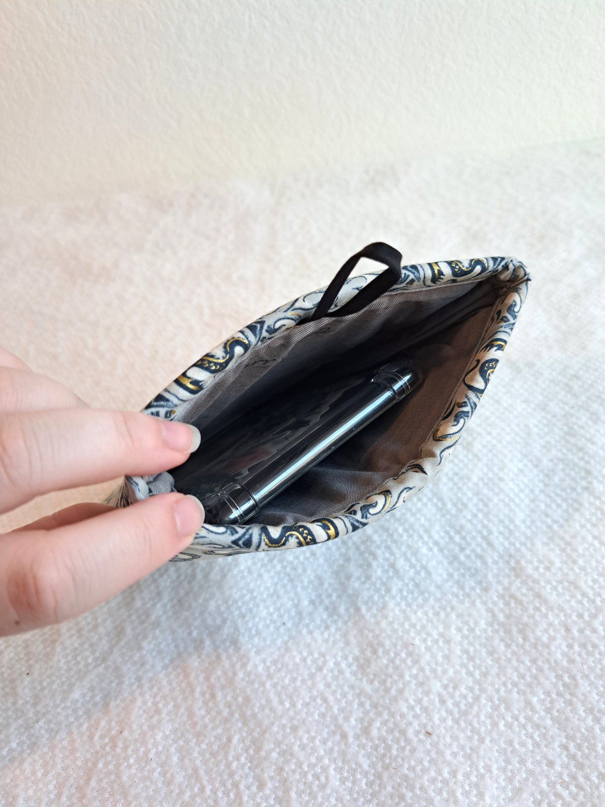white blanket background with the steel dragon kindle sleeve being held open with a kindle inside of it
